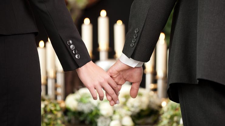 Hände eines Paares halten sich, umgeben von Kerzen und Blumenarrangements, in festlicher Atmosphäre.