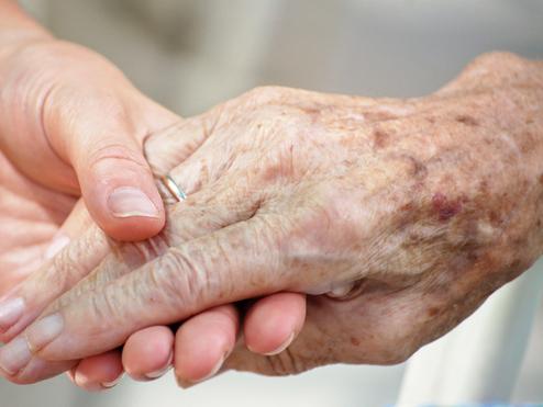 Nahaufnahme zweier Hände, eine ältere und eine jüngere, die sich liebevoll halten.